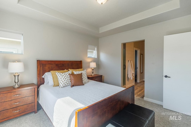 carpeted bedroom with a tray ceiling and a textured ceiling