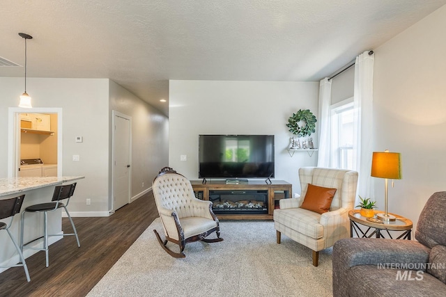 living room with separate washer and dryer, a textured ceiling, and dark wood-type flooring