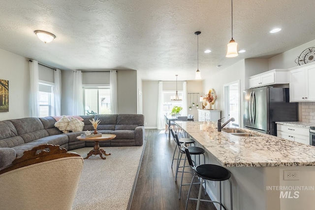 interior space with decorative light fixtures, dark hardwood / wood-style floors, sink, and white cabinetry