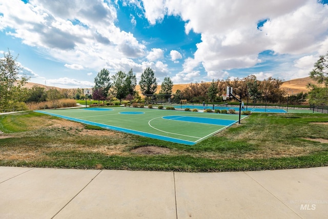 view of sport court with a mountain view and a lawn