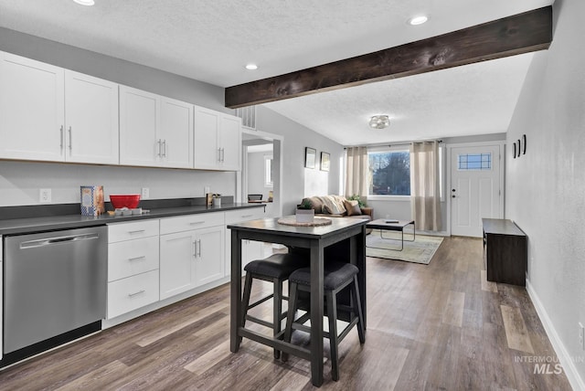 kitchen with white cabinetry, dark hardwood / wood-style floors, stainless steel dishwasher, and a textured ceiling