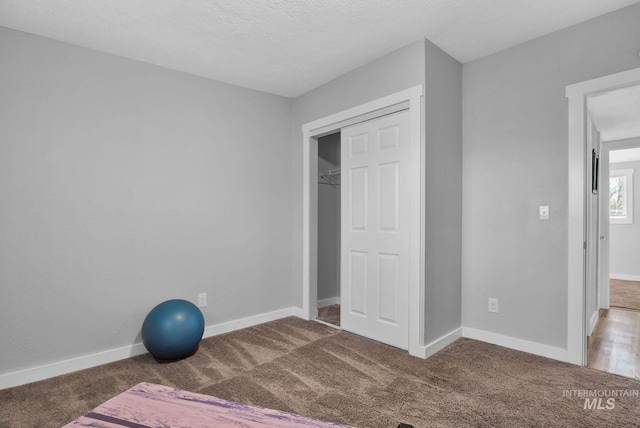 workout room featuring a textured ceiling and carpet flooring