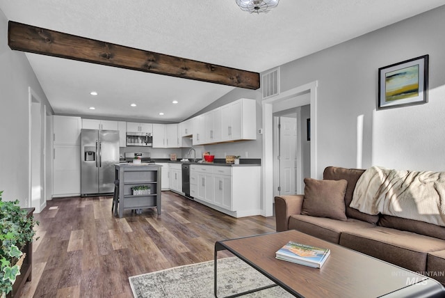 living room with dark hardwood / wood-style flooring, sink, vaulted ceiling with beams, and a textured ceiling