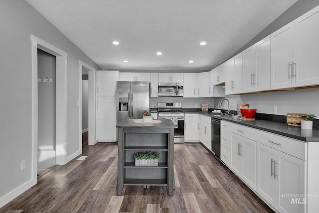 kitchen with a kitchen island, white cabinetry, appliances with stainless steel finishes, and dark hardwood / wood-style floors