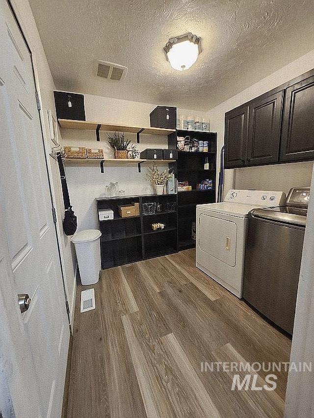 297 N 4228 E, Rigby, ID 83442 - laundry area with washing machine and clothes dryer, cabinet space, wood finished floors, and a textured ceiling
