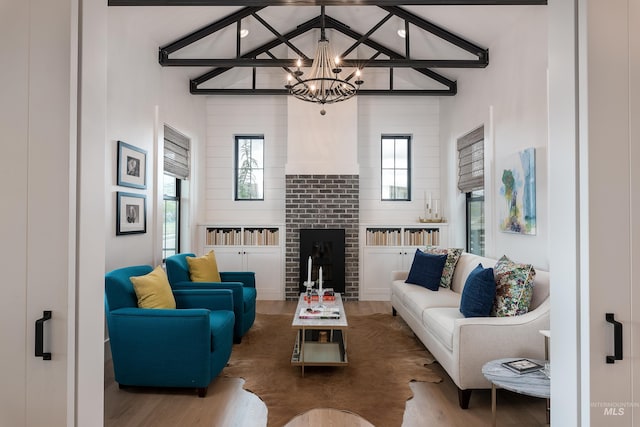 living room with a fireplace, lofted ceiling with beams, hardwood / wood-style floors, and a notable chandelier