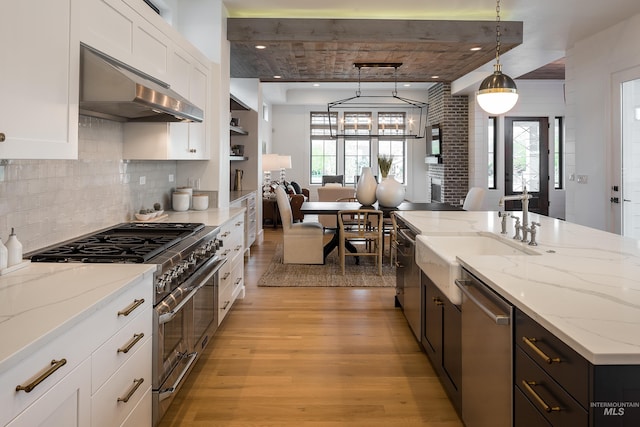 kitchen with white cabinets, appliances with stainless steel finishes, light stone counters, and pendant lighting