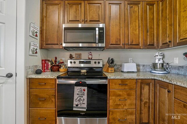 kitchen with appliances with stainless steel finishes and light stone counters