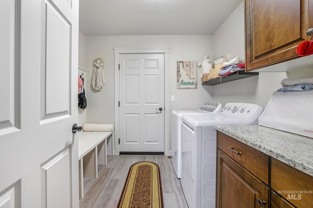 washroom with cabinets, light hardwood / wood-style flooring, and washing machine and clothes dryer