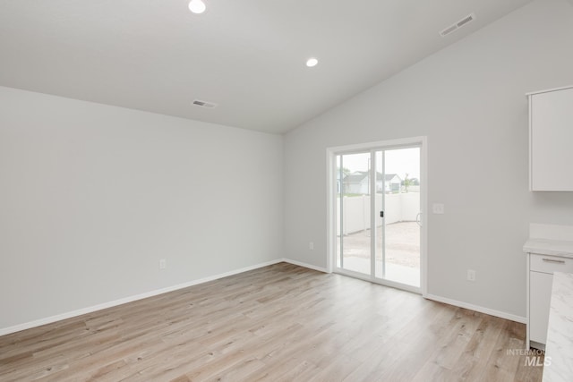 unfurnished room with light hardwood / wood-style floors and lofted ceiling