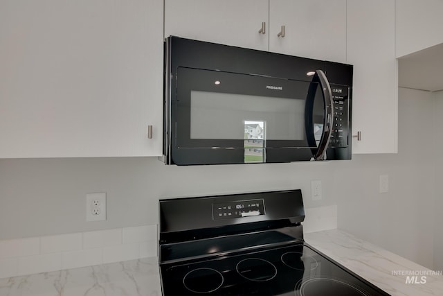 room details featuring light stone counters, white cabinetry, and range