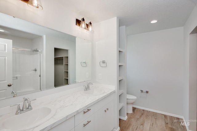 bathroom with built in shelves, walk in shower, toilet, vanity, and hardwood / wood-style flooring