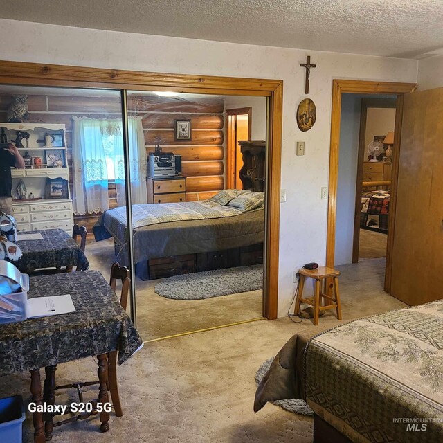 1050 Maxwell Ln, Elk City, ID 83525 - bedroom with log walls, a textured ceiling, and carpet flooring