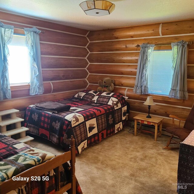 1050 Maxwell Ln, Elk City, ID 83525 - carpeted bedroom with log walls and a baseboard heating unit