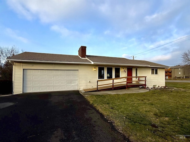 ranch-style home featuring a garage, a front yard, driveway, and a chimney