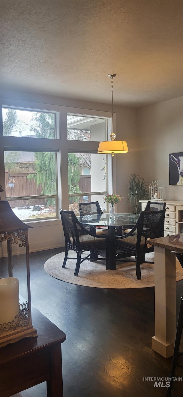 dining room with dark wood-type flooring and a textured ceiling