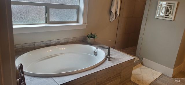 bathroom with tiled tub and a wealth of natural light