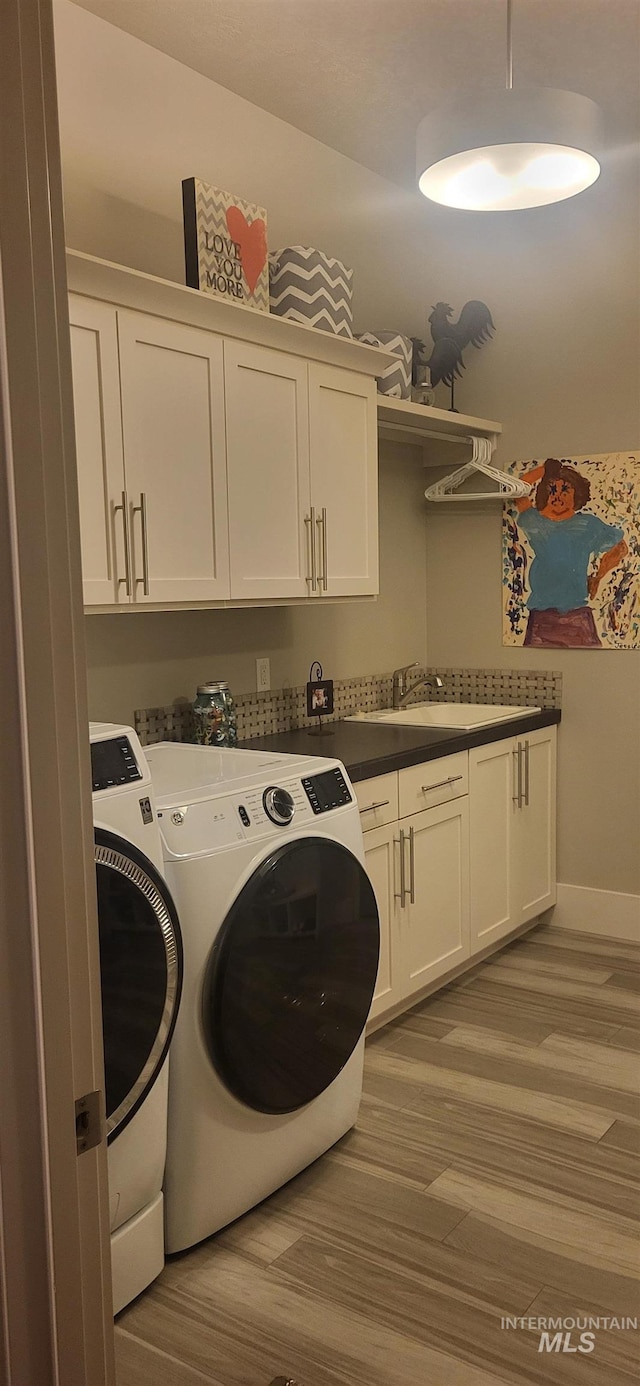 laundry room with cabinets, sink, independent washer and dryer, and light hardwood / wood-style floors