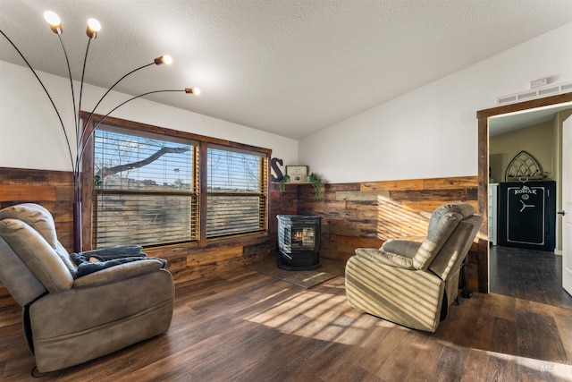 living area with lofted ceiling, a wood stove, wood finished floors, and visible vents