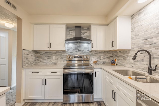 kitchen featuring white cabinets, appliances with stainless steel finishes, sink, and wall chimney range hood