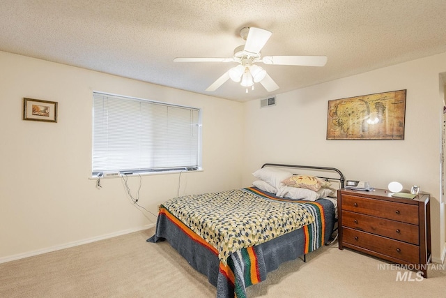 carpeted bedroom featuring ceiling fan and a textured ceiling