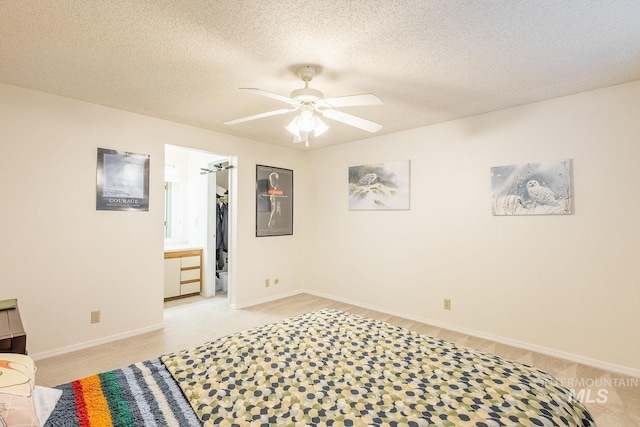 bedroom featuring ceiling fan, a spacious closet, light carpet, and a textured ceiling