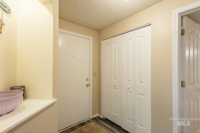 doorway to outside with dark wood-type flooring and a textured ceiling