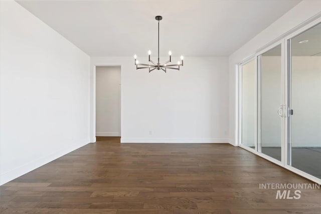 unfurnished dining area featuring baseboards, wood finished floors, and a chandelier
