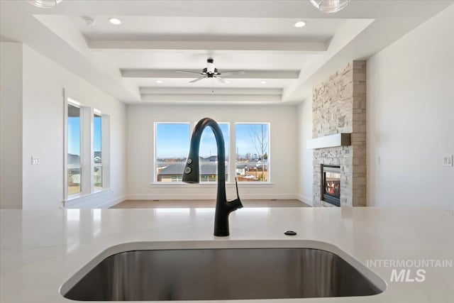 room details featuring a fireplace, a raised ceiling, recessed lighting, and a sink