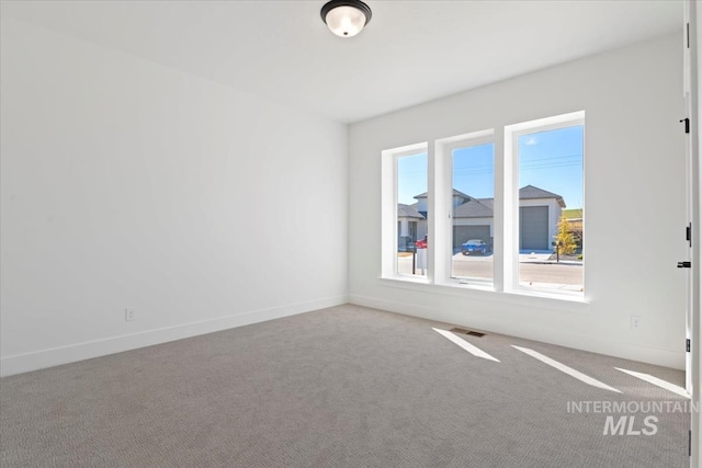 carpeted empty room with visible vents and baseboards