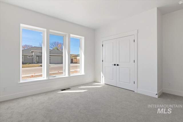 unfurnished bedroom featuring baseboards, visible vents, carpet floors, and a closet