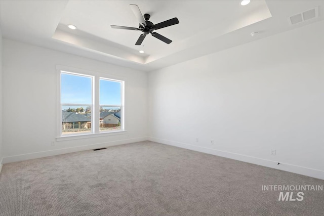 unfurnished room with baseboards, visible vents, recessed lighting, and a tray ceiling