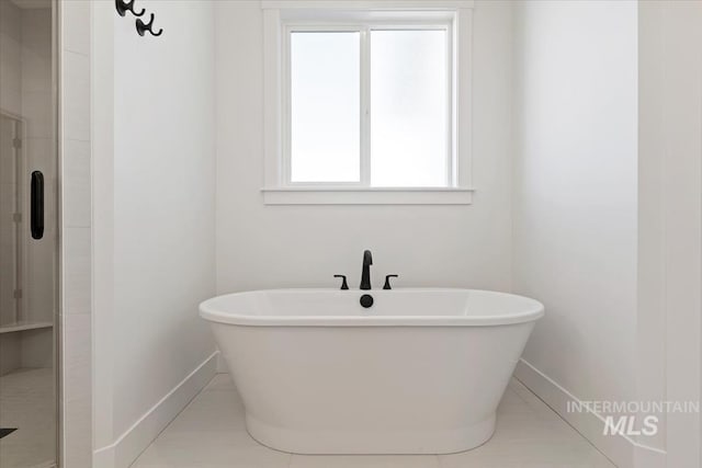 bathroom featuring a soaking tub, baseboards, tile patterned flooring, and a shower stall