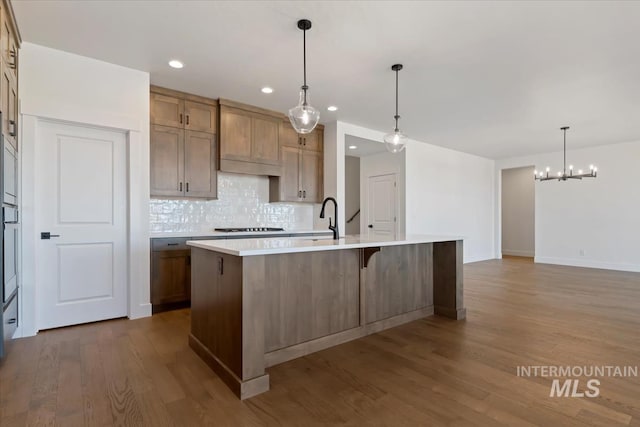 kitchen featuring light countertops, tasteful backsplash, wood finished floors, and a chandelier