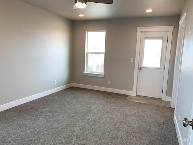 spare room featuring dark carpet and ceiling fan