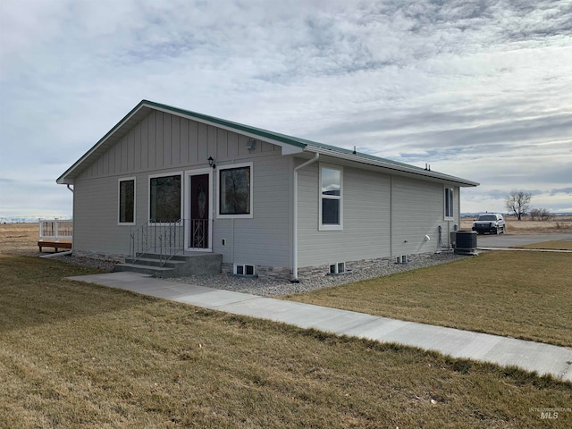 view of side of home featuring central AC and a lawn