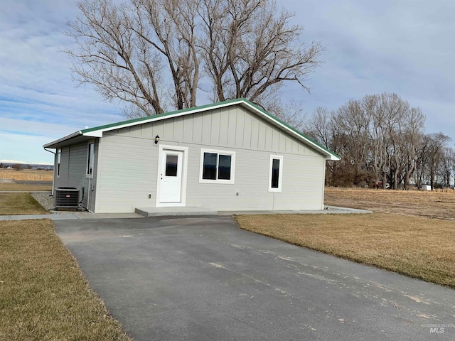 exterior space with central AC unit and a lawn