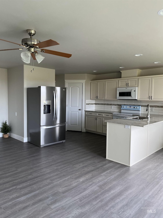 kitchen with appliances with stainless steel finishes, tasteful backsplash, ceiling fan, and dark hardwood / wood-style flooring