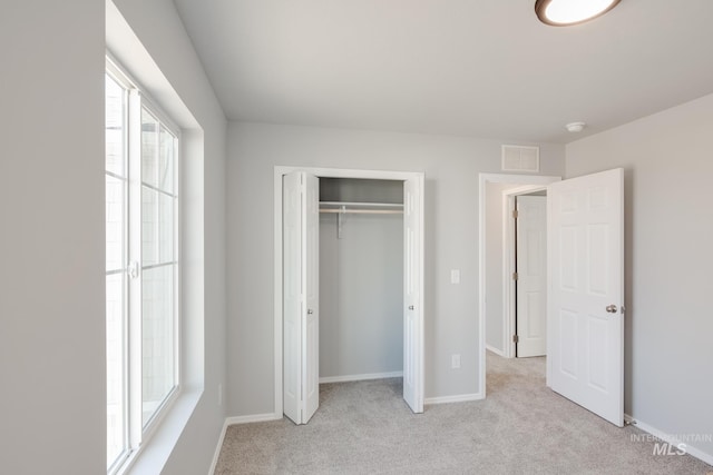 unfurnished bedroom featuring light carpet and a closet