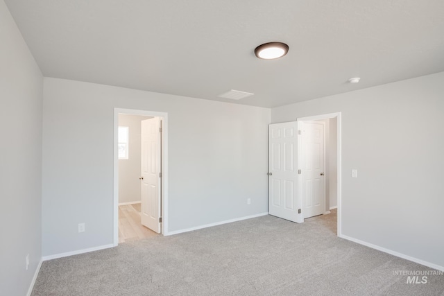 unfurnished bedroom featuring light colored carpet and ensuite bath