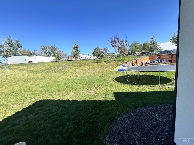 view of green lawn featuring a trampoline