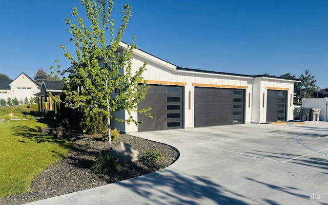 view of property exterior with board and batten siding, a garage, concrete driveway, and a yard