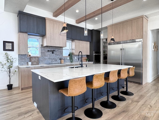 kitchen featuring stainless steel appliances, a sink, modern cabinets, a textured ceiling, and tasteful backsplash