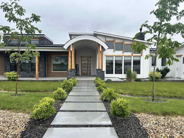 15006 Snow Mountain Dr, Caldwell, ID 83607 - contemporary house featuring a front yard, stone siding, a chimney, stucco siding, and a porch
