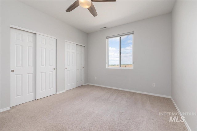 9805 Salmon Ridge Pl, Nampa, ID 83686 - unfurnished bedroom with multiple closets, light colored carpet, baseboards, and ceiling fan