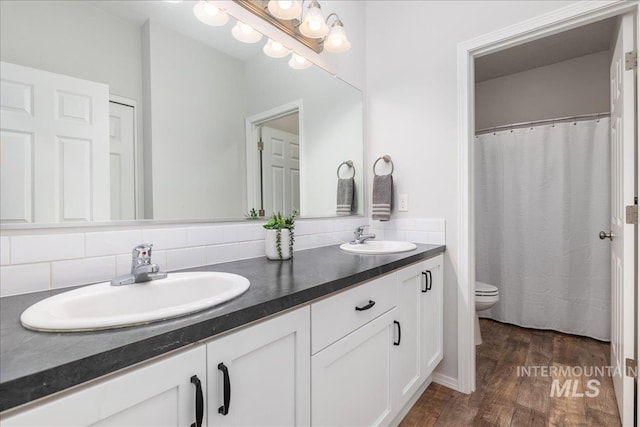 9805 Salmon Ridge Pl, Nampa, ID 83686 - bathroom with double vanity, toilet, wood finished floors, and backsplash