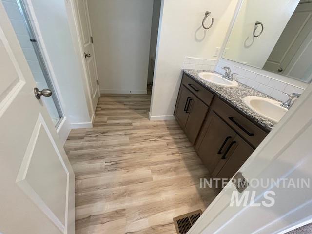 bathroom with vanity, hardwood / wood-style flooring, and tasteful backsplash