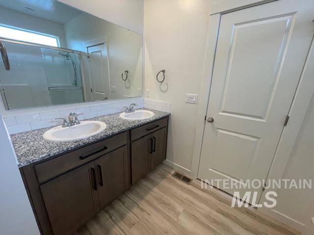 bathroom featuring decorative backsplash, hardwood / wood-style floors, vanity, and walk in shower