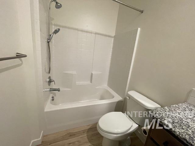 bathroom with wood-type flooring, bathing tub / shower combination, and toilet