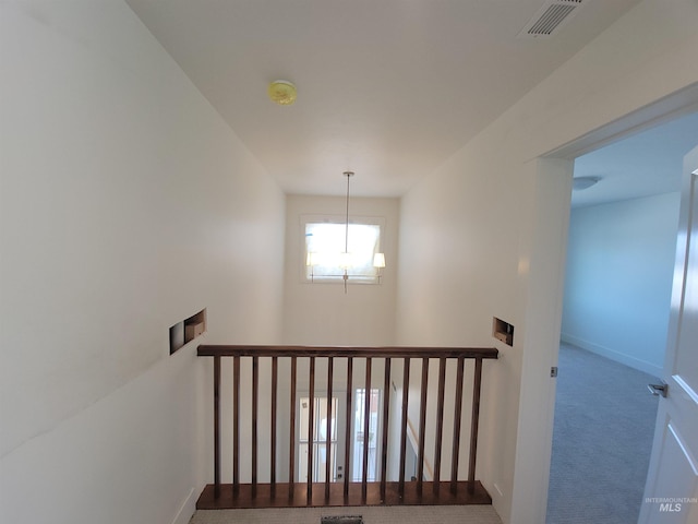 stairway with carpet floors, a chandelier, visible vents, and baseboards